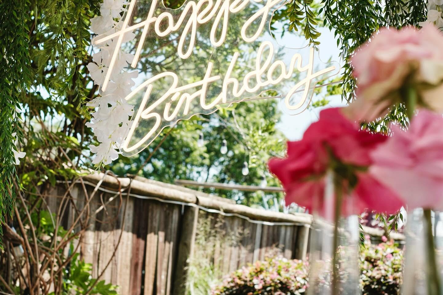 Neon birthday sign among foliage and garden roses