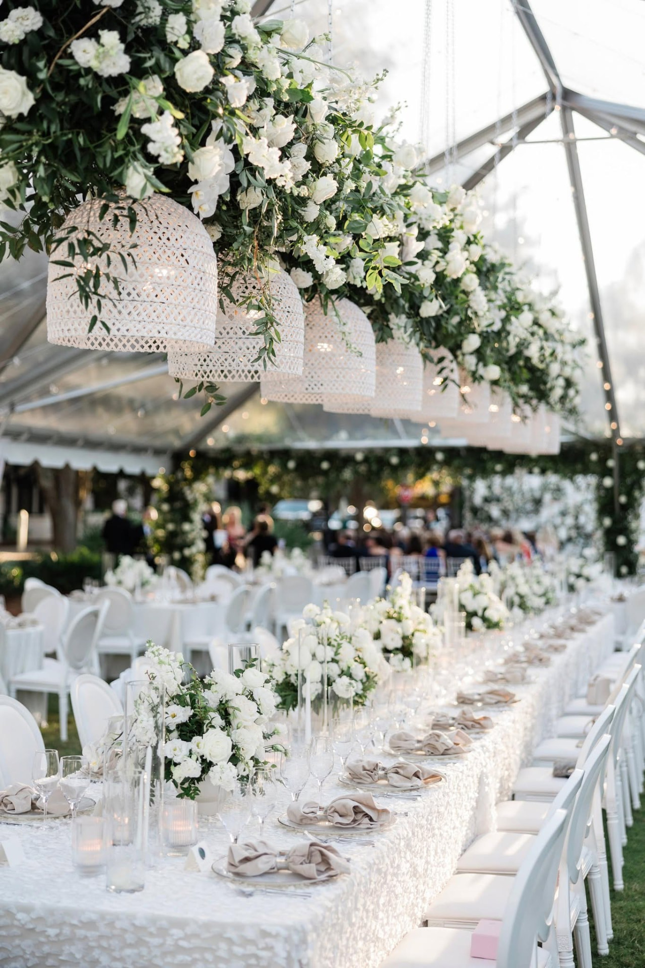 An elegant marquee reception at Aurum Sky with cascading white florals and woven chandeliers
