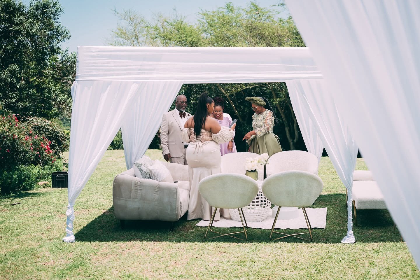 Family gathered in a white draped cabana lounge on the lawn