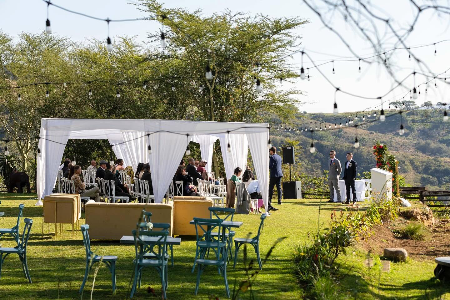 Guests seated under white cabanas for a lawn ceremony
